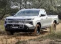 Toyota Hilux 2027 prata, cabine simples, em trilha de terra, novo visual e grade marcante