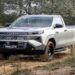 Toyota Hilux 2027 prata, cabine simples, em trilha de terra, novo visual e grade marcante