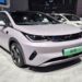 BYD Dolphin Mini branco em exposição, placas verdes e ambiente de salão automotivo chinês
