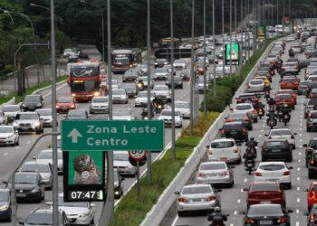 Congestionamento na Radial Leste com placa indicando Zona Leste e Centro, carros e ônibus em múltiplas faixas
