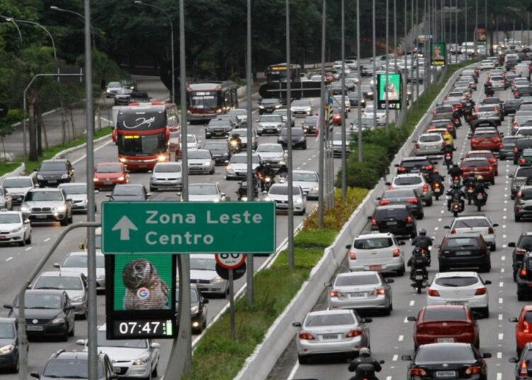 Congestionamento na Radial Leste com placa indicando Zona Leste e Centro, carros e ônibus em múltiplas faixas