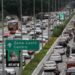 Congestionamento na Radial Leste com placa indicando Zona Leste e Centro, carros e ônibus em múltiplas faixas