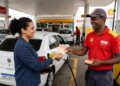 Motorista entrega notas de R$ 50 a frentista uniformizado Shell em bomba de combustível V-Power