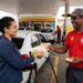 Motorista entrega notas de R$ 50 a frentista uniformizado Shell em bomba de combustível V-Power