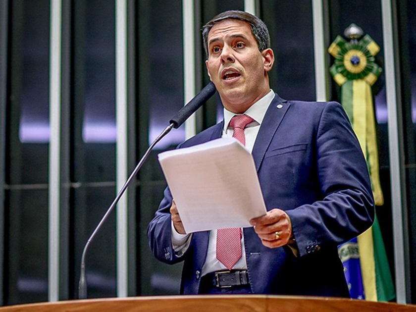 Deputado Amaro Neto (PP-ES) no plenário da Câmara segurando documentos durante discurso, usando terno azul e gravata vermelha