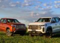 Duas picapes Ram Dakota 2026, uma laranja Laramie e outra branca Warlock, estacionadas em gramado verde sob céu azul