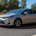 Toyota Corolla sedan prata trafega em rodovia com fundo de vegetação verde, exibindo grade frontal com emblema da marca