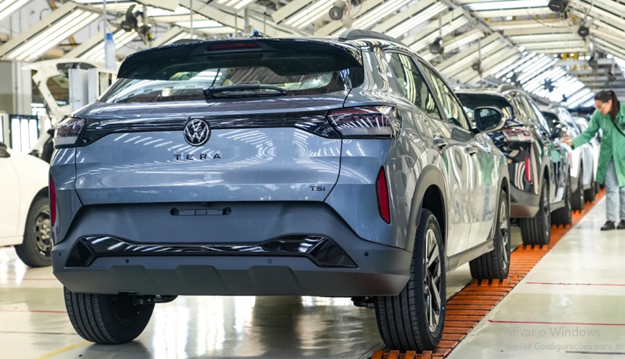 Volkswagen Tera azul TSI na linha de montagem em Taubaté, com funcionária ao fundo e esteira vermelha