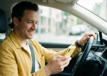 Motorista parceiro da 99 dentro de carro segurando celular durante parceria com a CAIXA para financiamento de veículo novo.