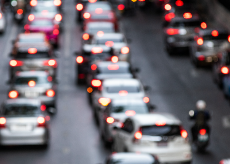 Trânsito intenso com carros e motos em avenida congestionada.