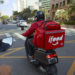 Entregador do iFood circula de moto em avenida na zona urbana.