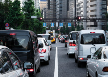 Trânsito intenso em avenida urbana durante sinal vermelho.