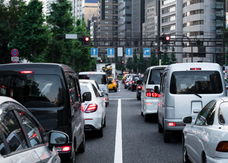Trânsito intenso em avenida urbana durante sinal vermelho.