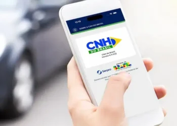 Pessoa acessa aplicativo CNH do Brasil no celular para realizar transferência digital de veículo.