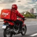 Entregador do iFood em motocicleta representa a entrega de medicamentos por aplicativos após decisão da Anvisa.