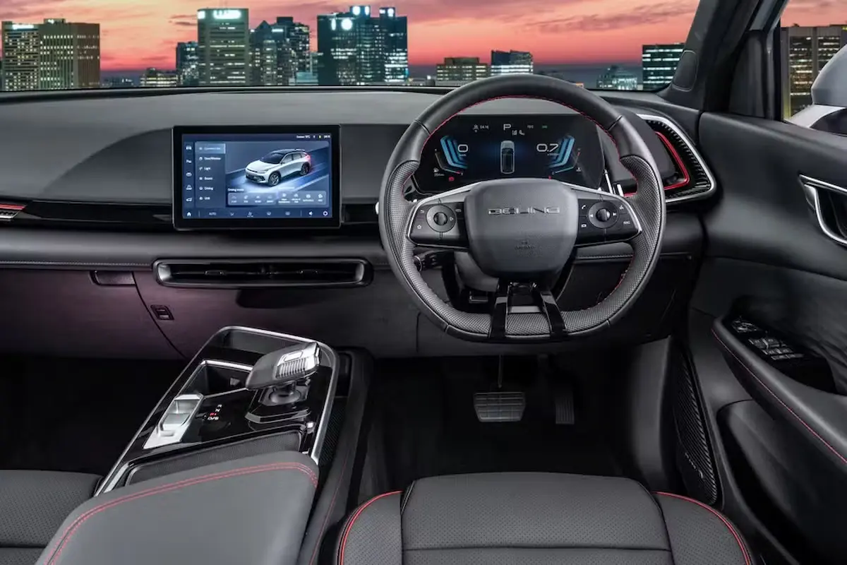 Interior do Baic X55 com console central elevado, painel digital e volante de desenho esportivo.