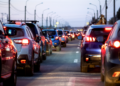Engarrafamento em avenida urbana ao entardecer com carros parados.
