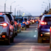 Engarrafamento em avenida urbana ao entardecer com carros parados.