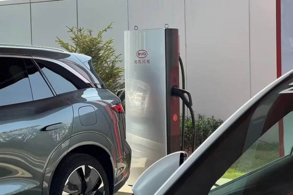 Carregador rápido da BYD para veículos elétricos ao lado de carros elétricos.