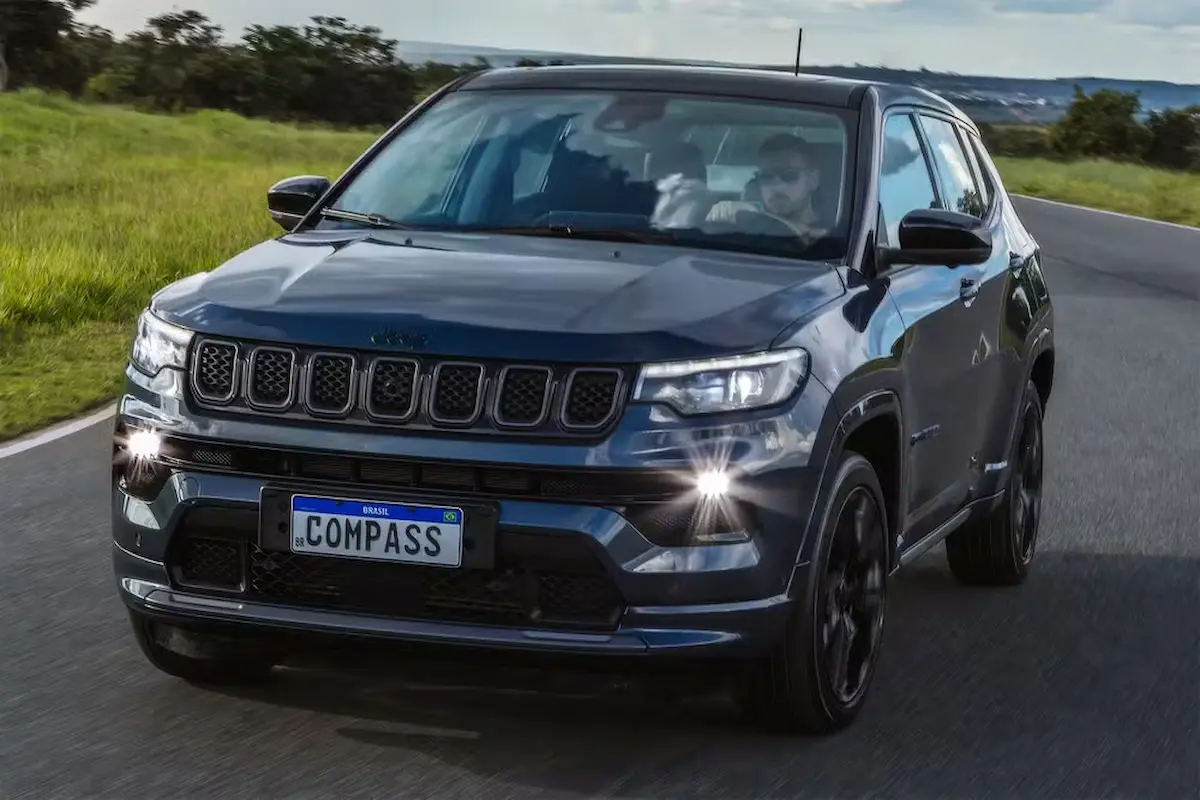 Jeep Compass 4xe híbrido plug-in em estrada com destaque para o sistema de recarga elétrica.