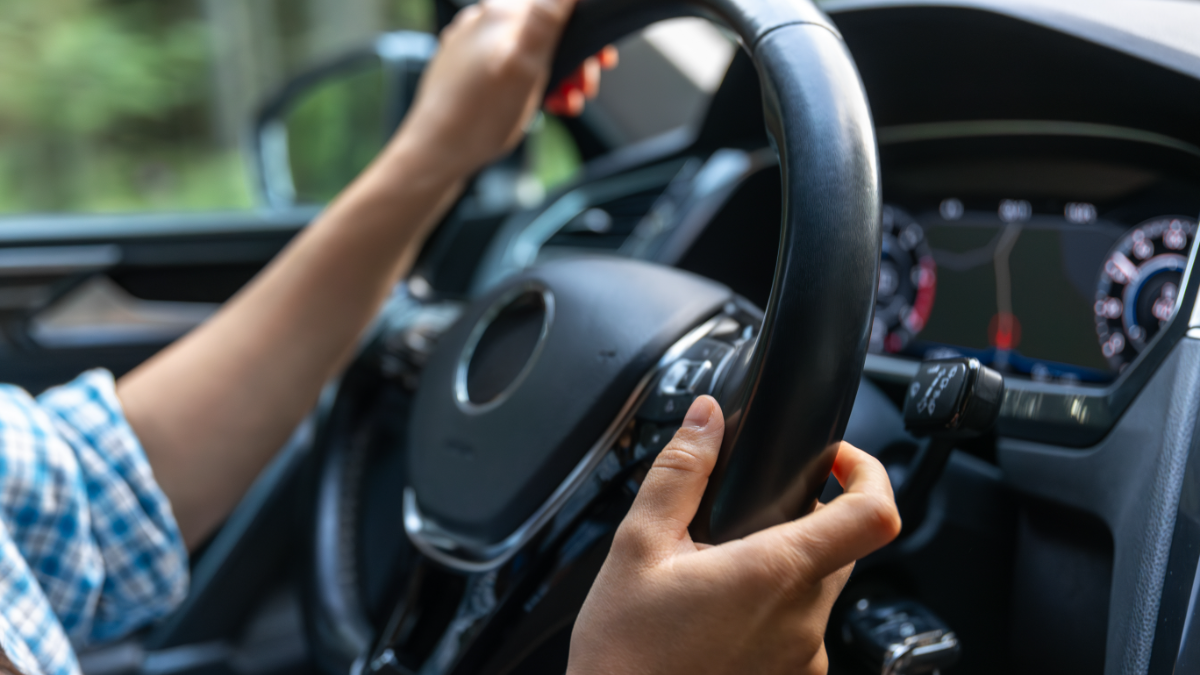 Motorista conduz carro moderno com painel digital em viagem.