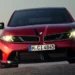 BMW esportivo vermelho com faróis acesos em destaque frontal.