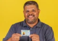 Homem segurando CNH e fundo amarelo.