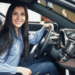 Mulher sorrindo ao volante de carro moderno em ambiente interno.