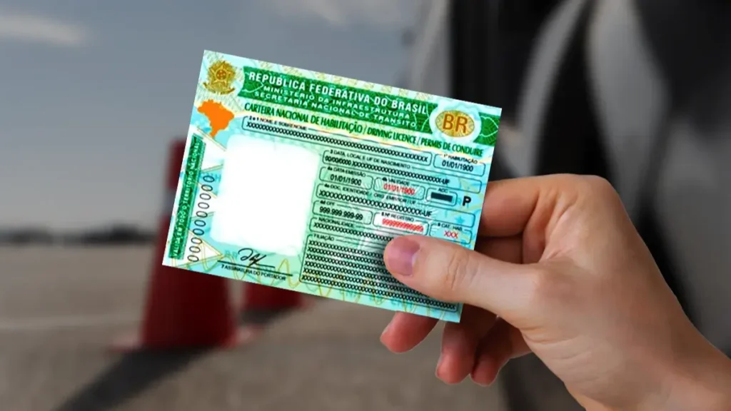 Pessoa exibe carteira de motorista CNH do Brasil ao lado de cones laranja na pista.