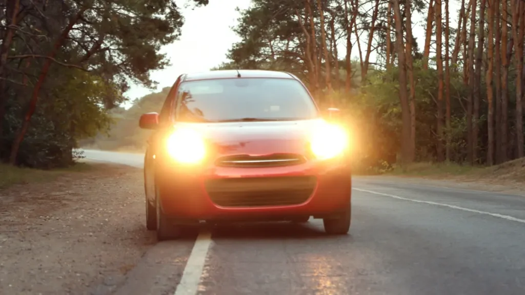 Carro vermelho com farol ligado.