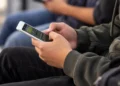 Universitário utiliza celular para acessar plataforma de apostas online.