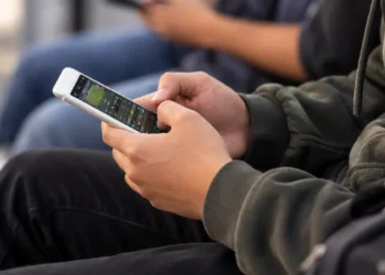 Universitário utiliza celular para acessar plataforma de apostas online.