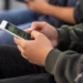 Universitário utiliza celular para acessar plataforma de apostas online.