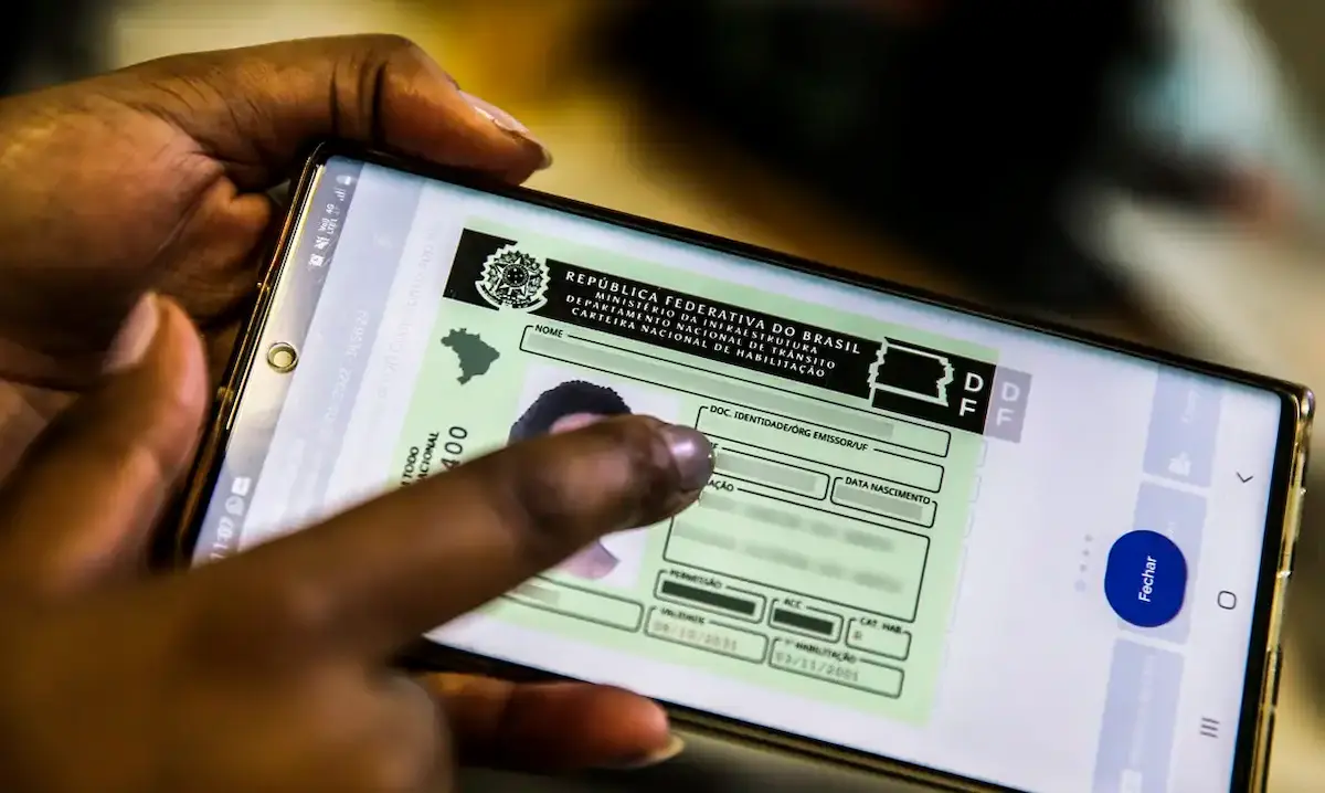 Motorista acessando a Carteira Nacional de Habilitação digital pelo celular após regras de suspensão da CNH.