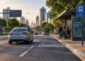 Carro circulando próximo ao ponto de ônibus em via urbana com sinalização de transporte coletivo.