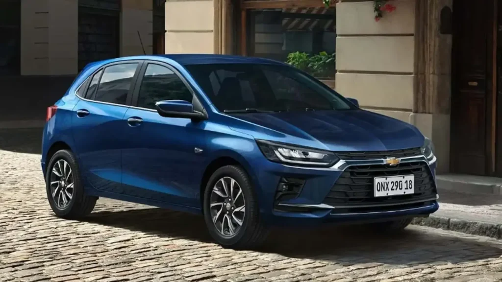 Chevrolet Onix azul estacionado em uma rua de paralelepípedos, visto de frente e de lado.