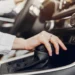 Mão sobre a alavanca de câmbio automático, com o console central do carro ao fundo.