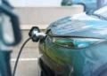 Carro elétrico conectado a um ponto de recarga, com destaque para o cabo e a parte dianteira do veículo.