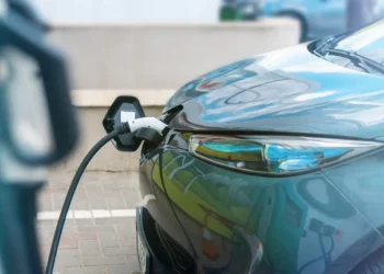 Carro elétrico conectado a um ponto de recarga, com destaque para o cabo e a parte dianteira do veículo.