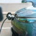 Carro elétrico conectado a um ponto de recarga, com destaque para o cabo e a parte dianteira do veículo.