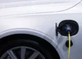 Carro elétrico branco com o cabo de recarga conectado à entrada de carga