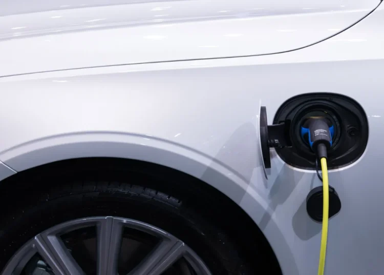 Carro elétrico branco com o cabo de recarga conectado à entrada de carga