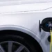 Carro elétrico branco com o cabo de recarga conectado à entrada de carga