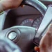 Mãos de um motorista segurando um celular junto ao volante do carro