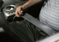 Mão de um motorista puxando o cinto de segurança no banco do carro