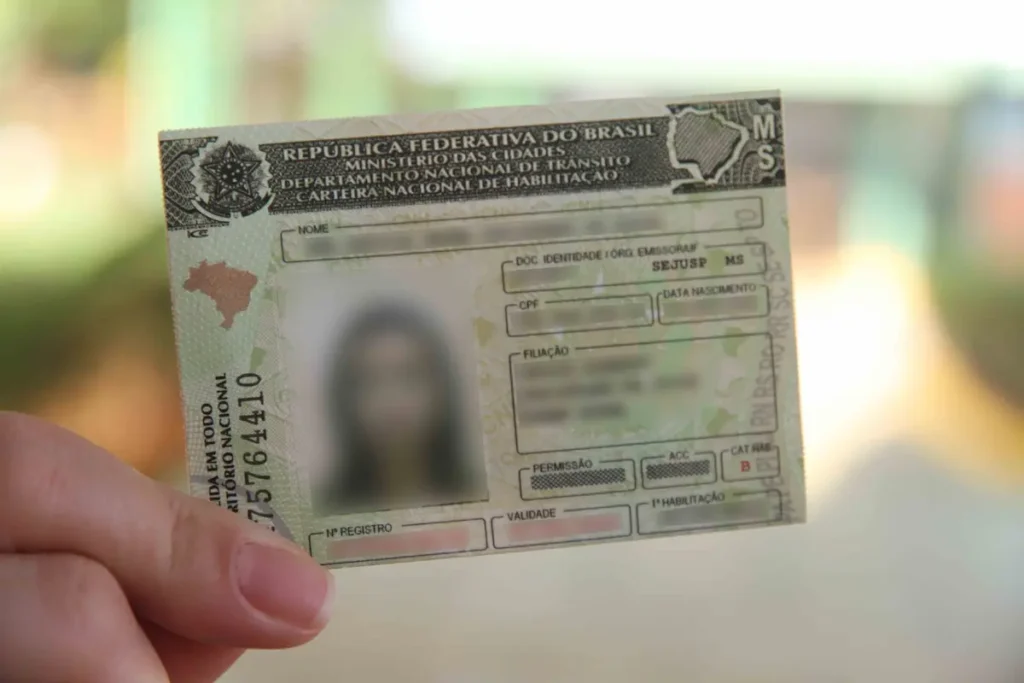 Motorista segura uma Carteira Nacional de Habilitação (CNH), representando processo do Detran-MS que pode resultar em suspensão ou cassação do documento.