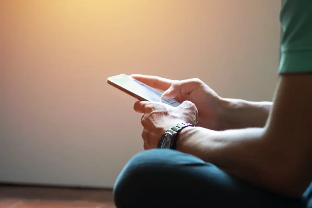 Homem utilizando celular para acessar serviços digitais, representando as melhorias de acessibilidade e navegação no novo portal do Detran-PB.