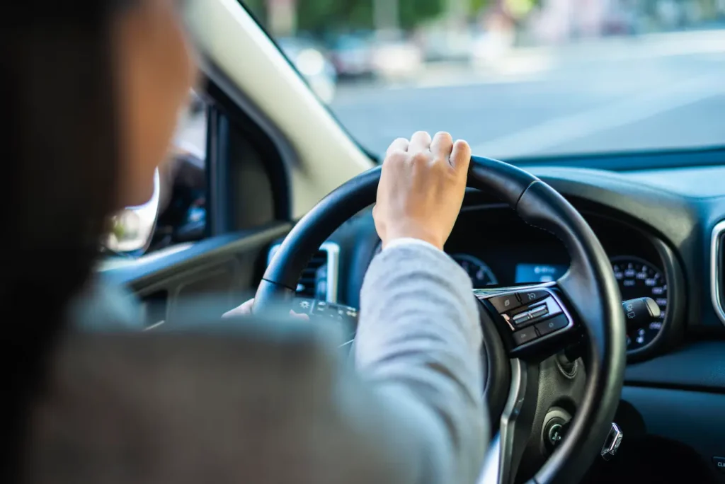 Motorista ao volante dirige com atenção em via urbana para manter a segurança no trânsito.